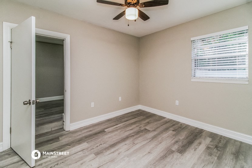 the interior of a room with wood flooring and a ceiling fan