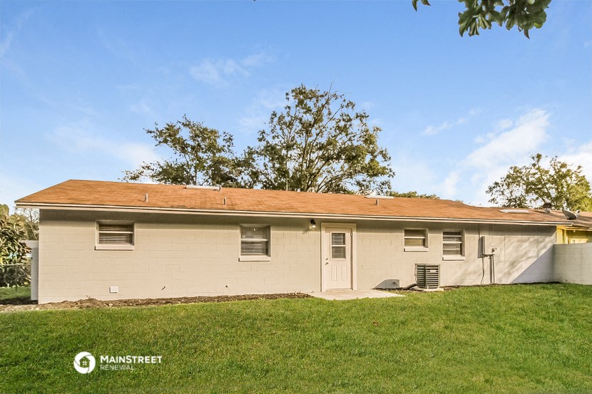 a small white house with a red roof on a grass field