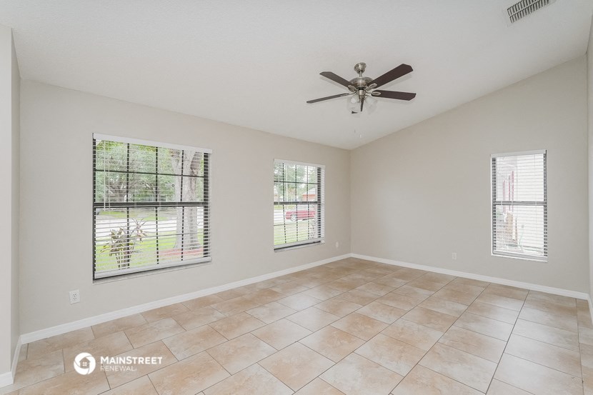 the living room of an empty home with a ceiling fan