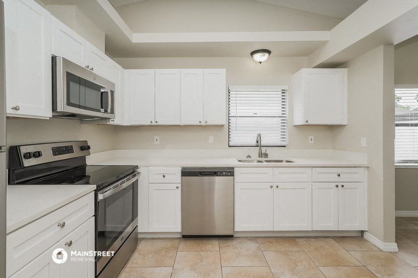 a kitchen with white cabinets and black appliances and a sink