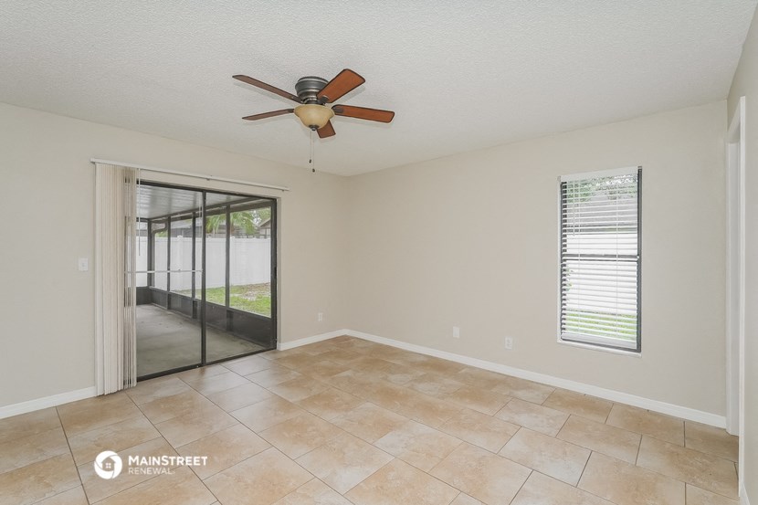 an empty living room with a ceiling fan and a sliding glass door