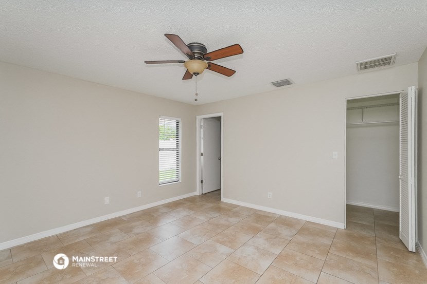 the spacious living room with ceiling fan and tile flooring