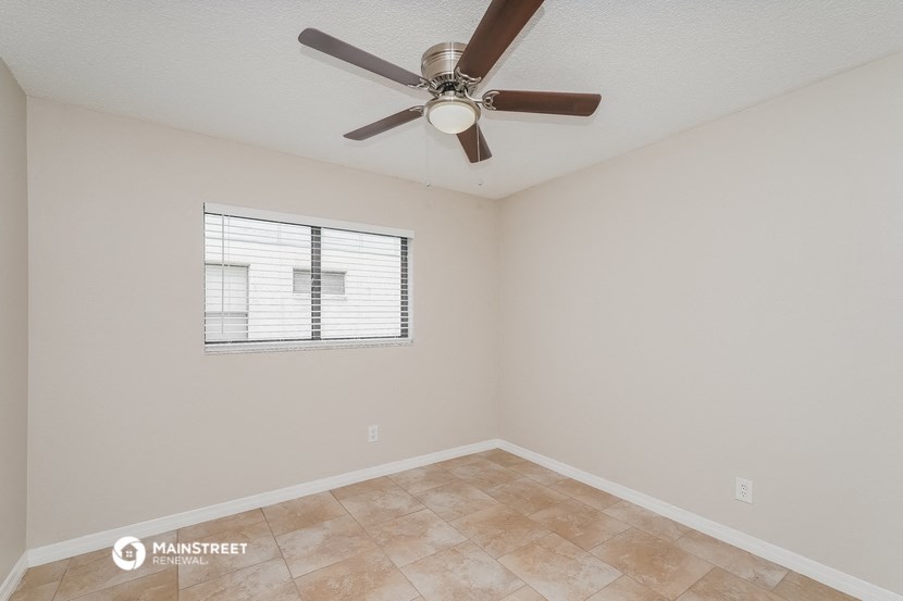 the spacious living room with ceiling fan and tile flooring