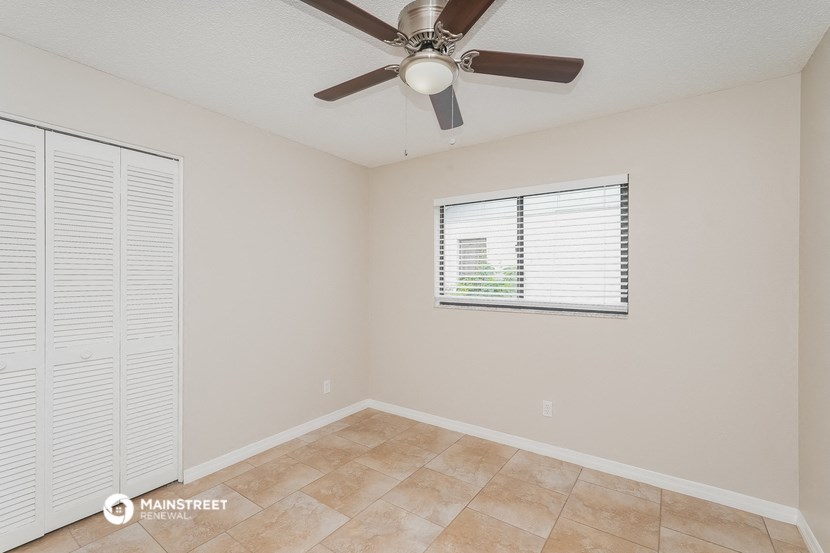 the spacious living room has a ceiling fan and a large window