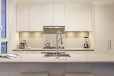 A modern kitchen with white cabinets and a stainless steel sink.