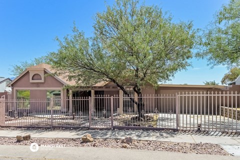 a house with a fence and a tree in front of it