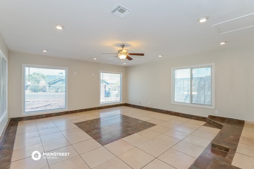 an empty living room with a ceiling fan and tiled floors