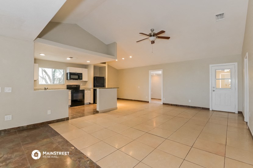 the spacious living room and kitchen with tile flooring and a ceiling fan
