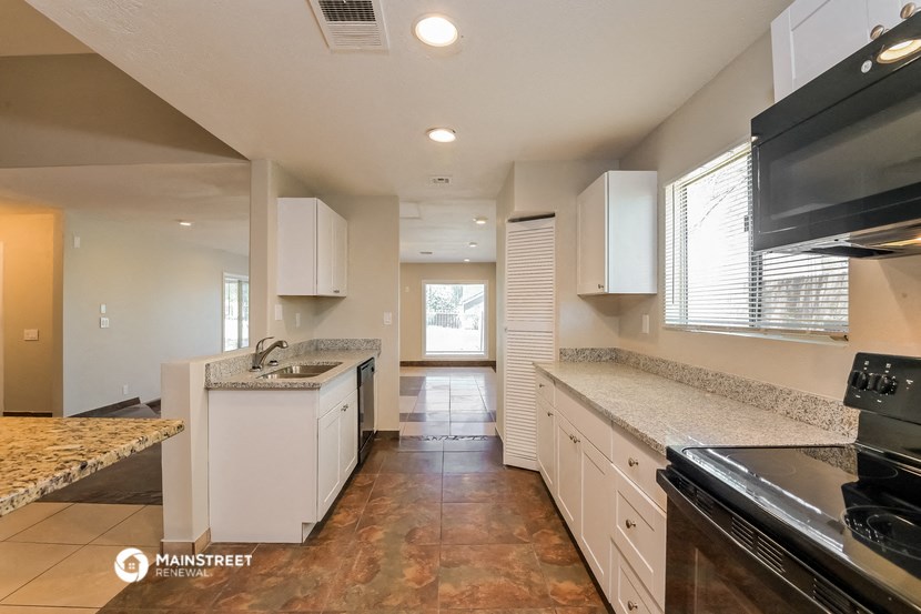 a kitchen with white cabinets and granite counter tops and a black stove