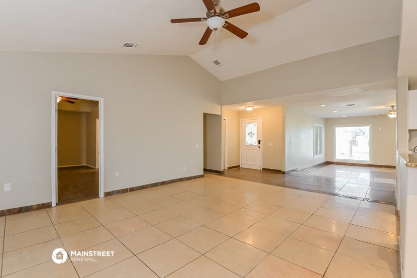 an empty living room with tiled floors and a ceiling fan