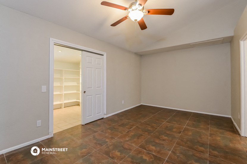 the living room of a home with a closet and a ceiling fan