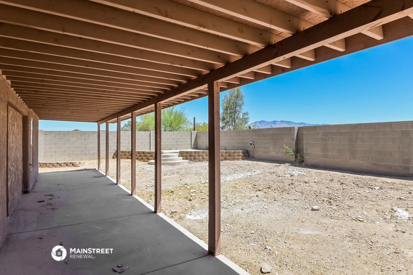 a covered walkway under a roof in a dirt field