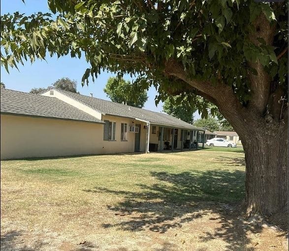 A tree is in the foreground of a house with a car in the driveway.