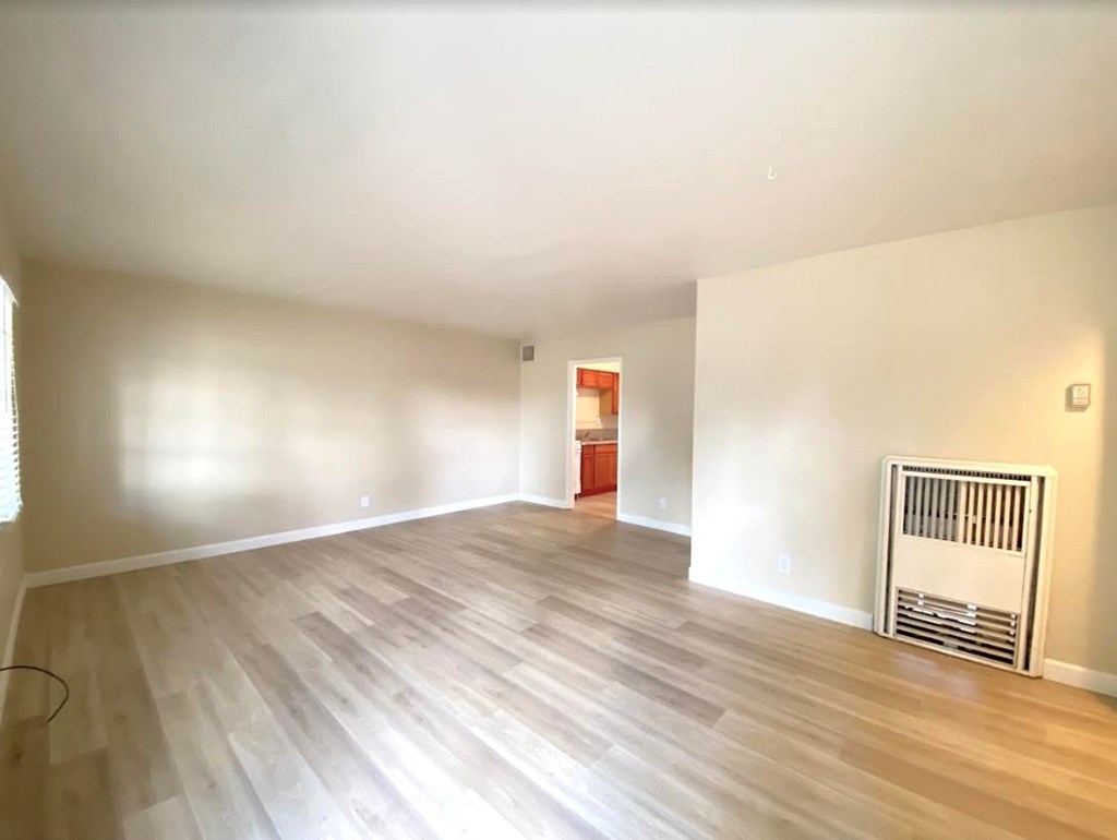 A room with wooden flooring and a radiator on the wall.