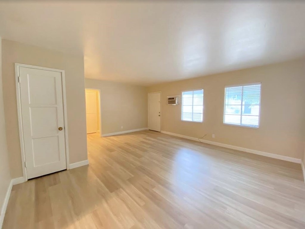 A room with a white door and wooden flooring.