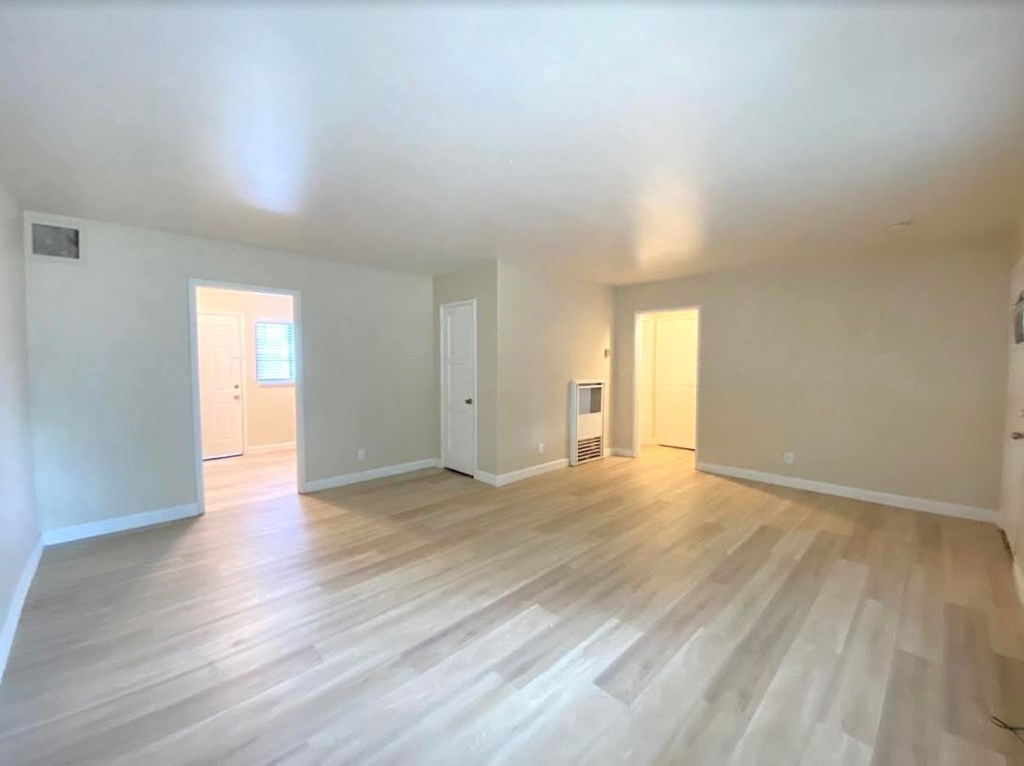 A spacious room with wooden flooring and white walls.