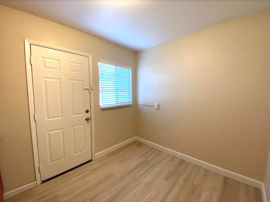 A room with a white door and a window with blinds.
