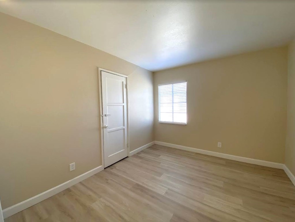 A room with a white door and a window with blinds.