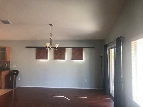 an empty living room with three windows and a chandelier