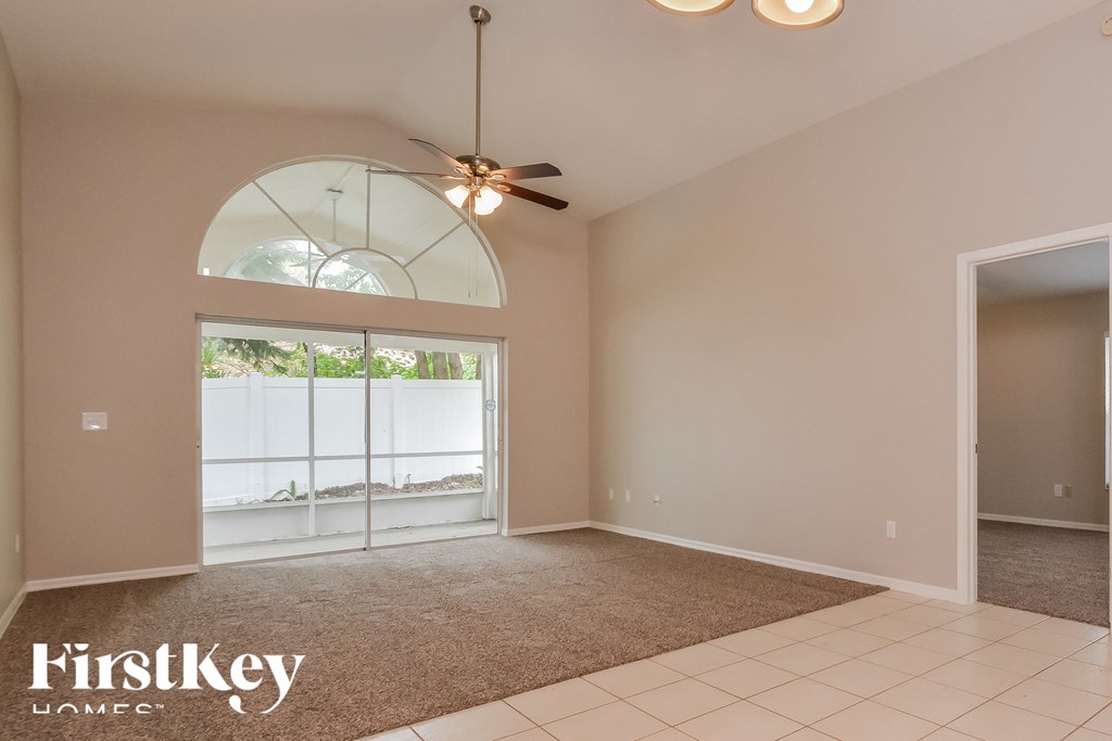 an empty living room with a ceiling fan and a window