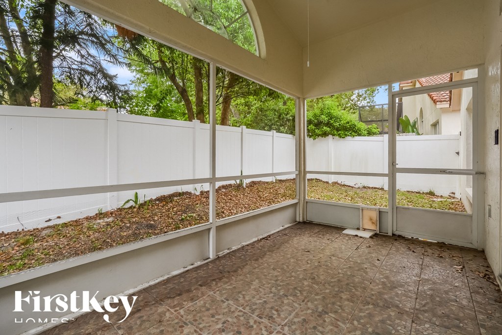 a porch with a white fence and a garden behind it