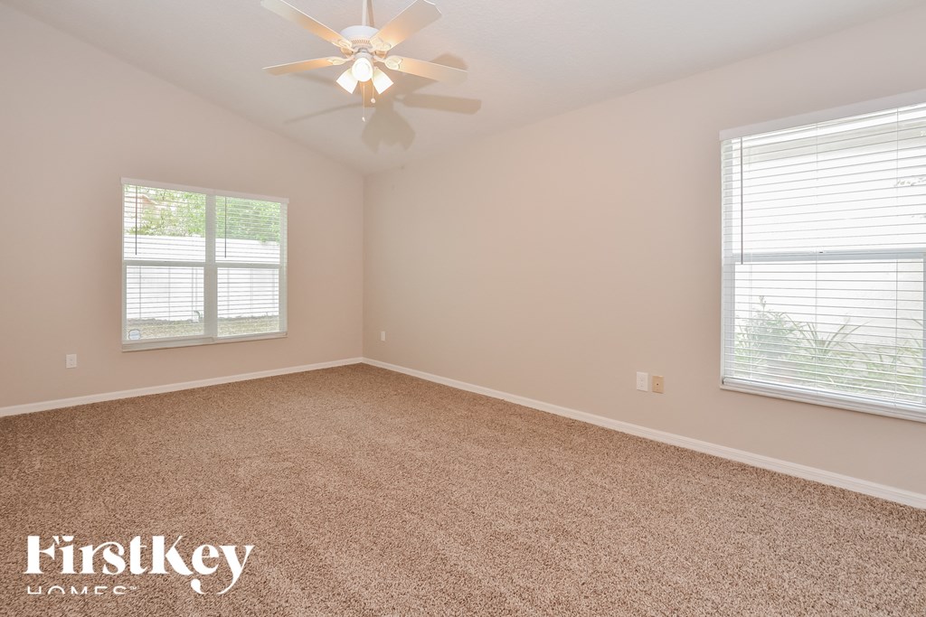 a bedroom with carpet and a ceiling fan and two windows