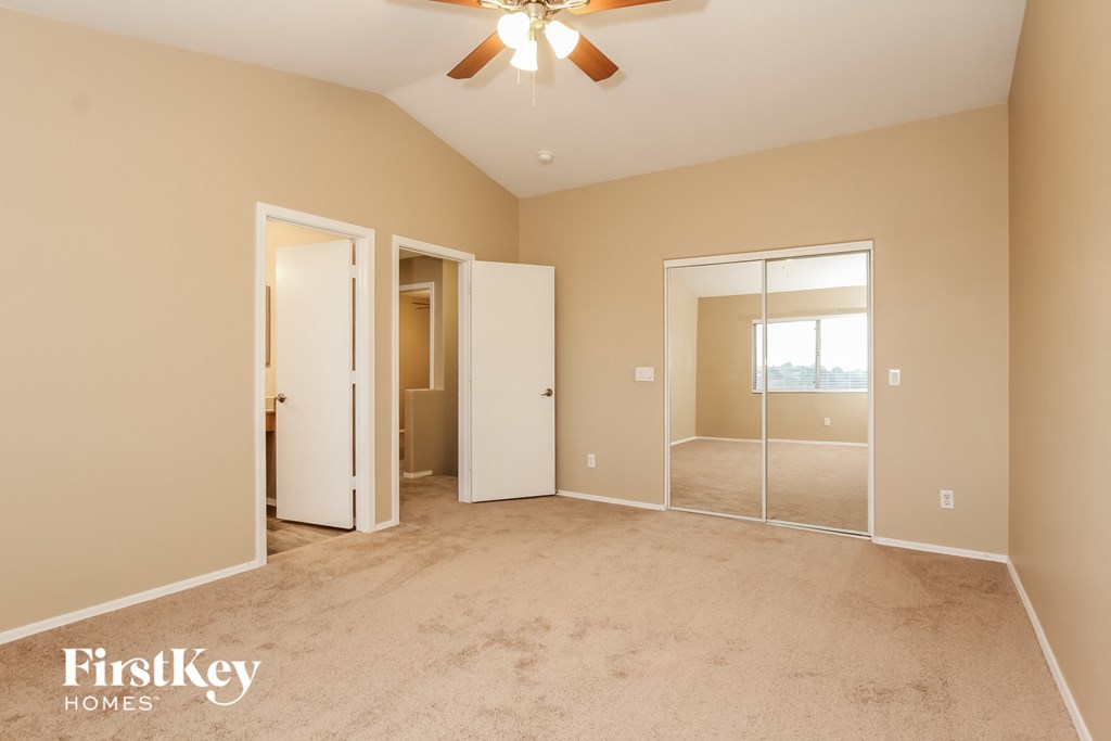 a master bedroom with carpet and a ceiling fan