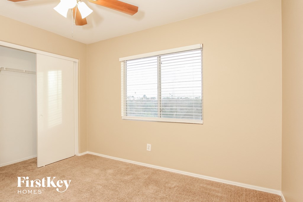 a bedroom with a large window and a ceiling fan