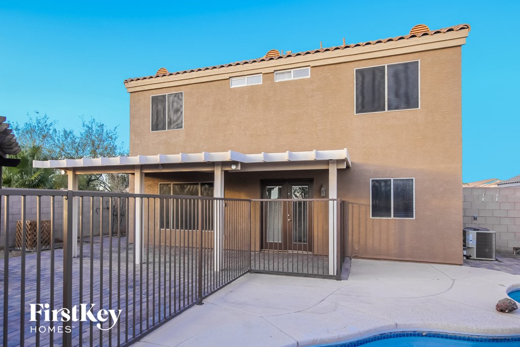 a home with a pool and a fence in front of it
