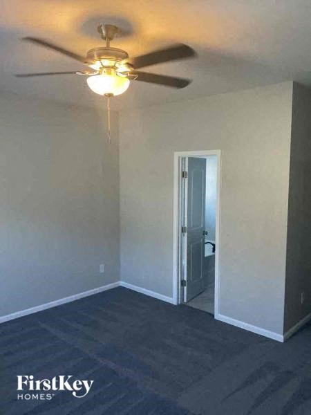 an empty room with a ceiling fan and a door to a bathroom