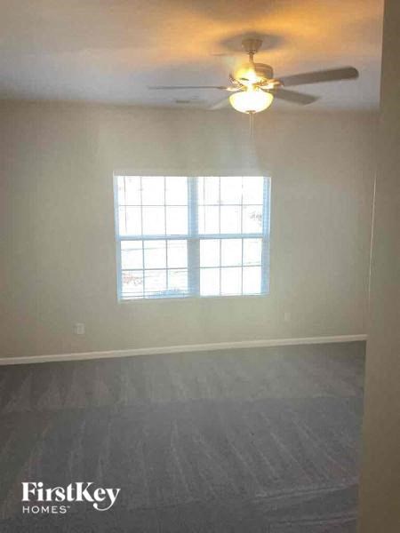 an empty living room with a ceiling fan and a window