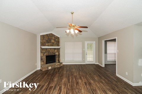 A room with a stone fireplace and a ceiling fan.