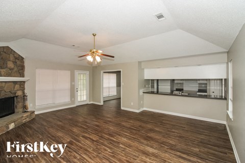 A spacious room with wood flooring and a ceiling fan.