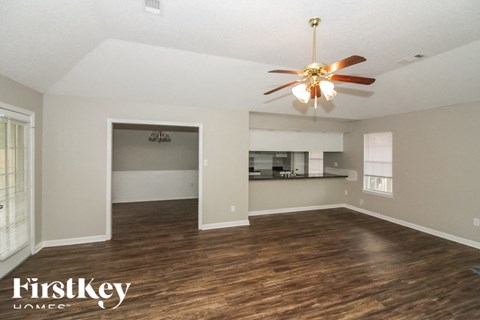 A spacious room with a ceiling fan and wooden flooring.