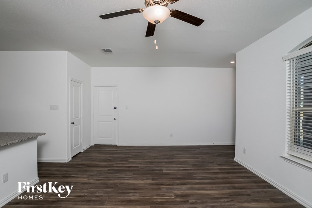 a living room with white walls and a ceiling fan