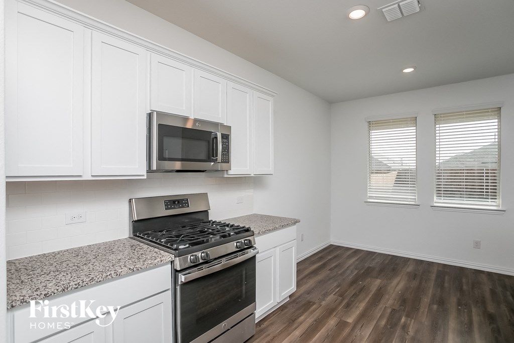 a kitchen with white cabinets and a stove and a microwave