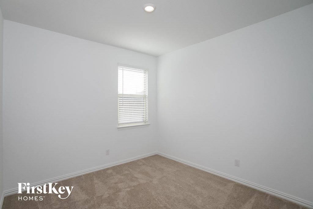 a bedroom with white walls and carpet and a window
