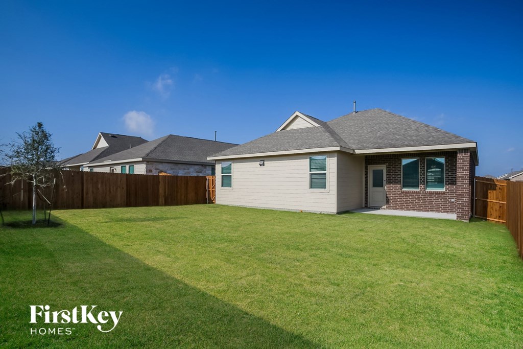 a backyard with a white house and a fence