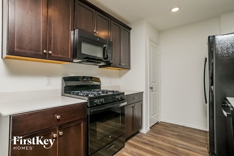 A kitchen with wooden cabinets and a black fridge.