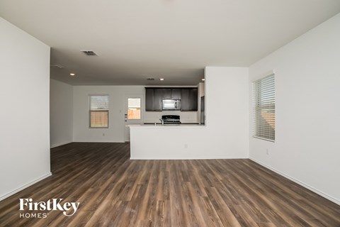 A spacious living room with wooden floors and a television.
