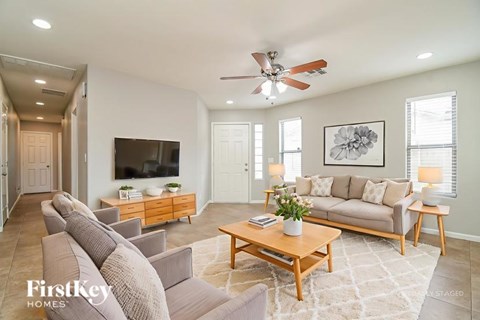 A living room with a grey couch, a wooden coffee table, and a ceiling fan.