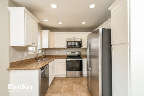 A kitchen with a refrigerator, sink, and microwave.