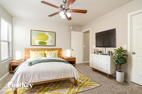 A bedroom with a bed, a dresser, a ceiling fan, and a painting on the wall.