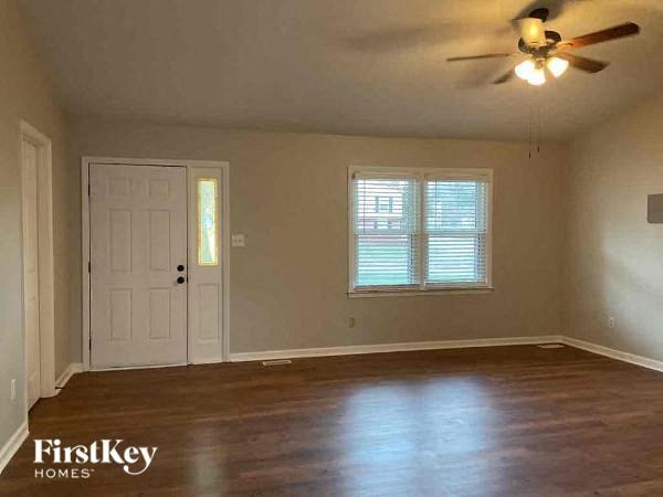 an empty living room with a ceiling fan and a white door