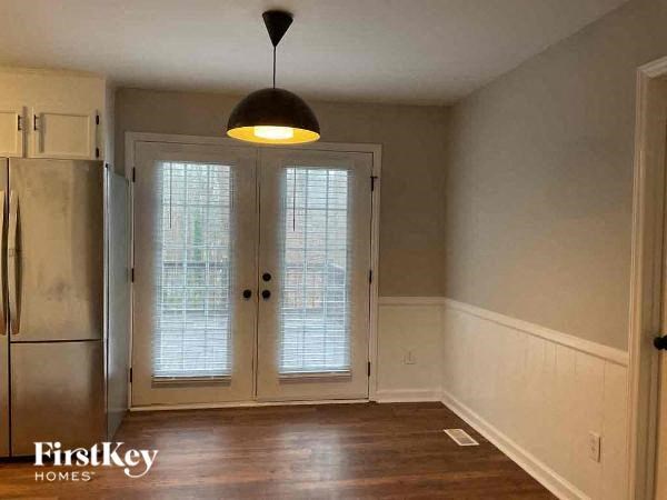 an empty living room with a refrigerator and a door