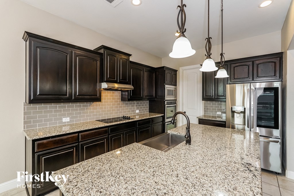a kitchen with black cabinets and a marble counter top