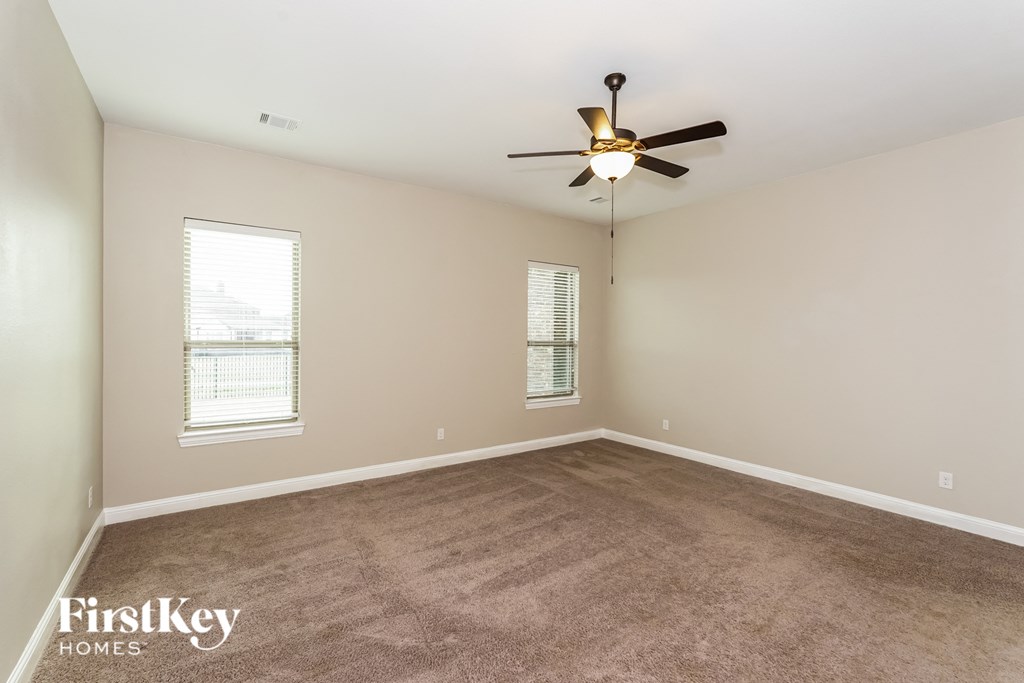 the spacious living room with carpet and a ceiling fan