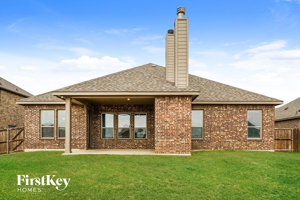 a view of a brick house with a porch and a lawn