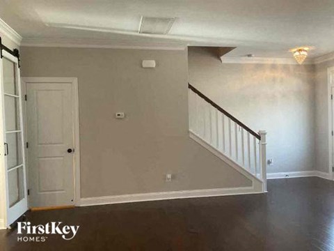 an empty living room with a white door and a staircase