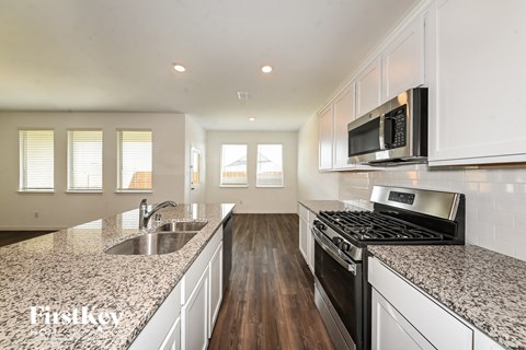 A kitchen with white cabinets and a granite countertop.